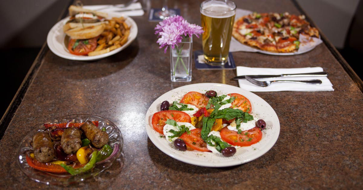Caprese salad, sausages, and pizzas on a table at Bruno's
